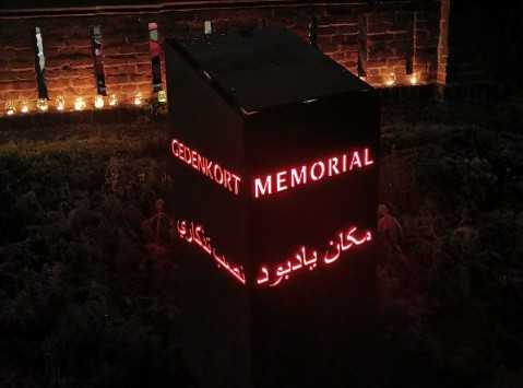Foto: Das beleuchtete Denkmal mit Kerzen vor der Mauer